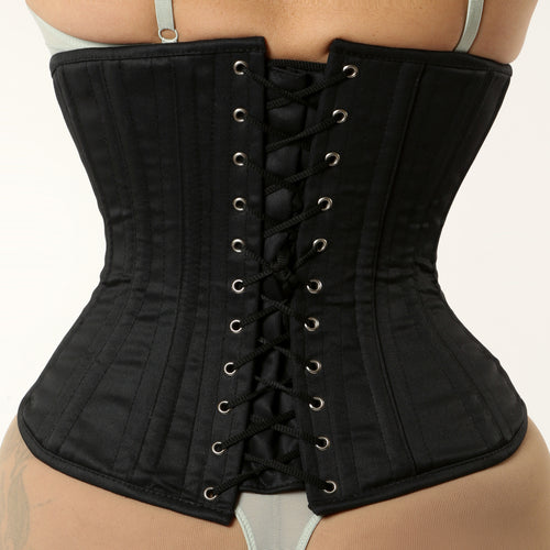 Black corset worn by a person on a plain background