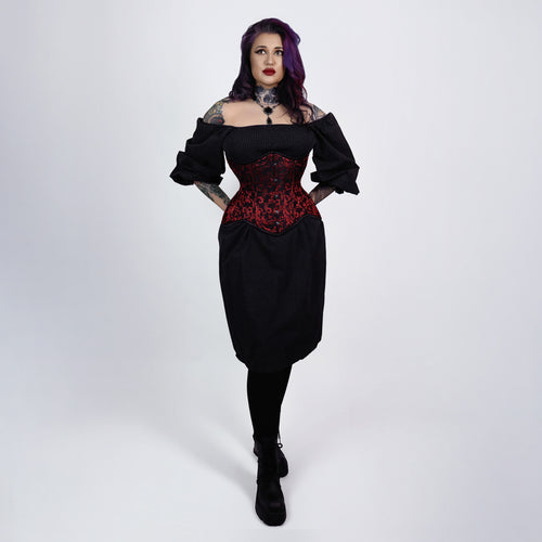 Woman wearing a black dress with a red corset top on a white background